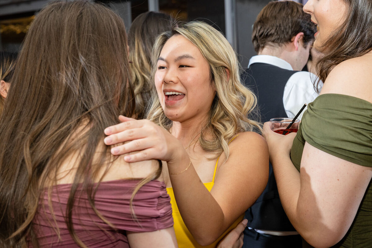 A woman in a yellow tank top is hugging another woman.