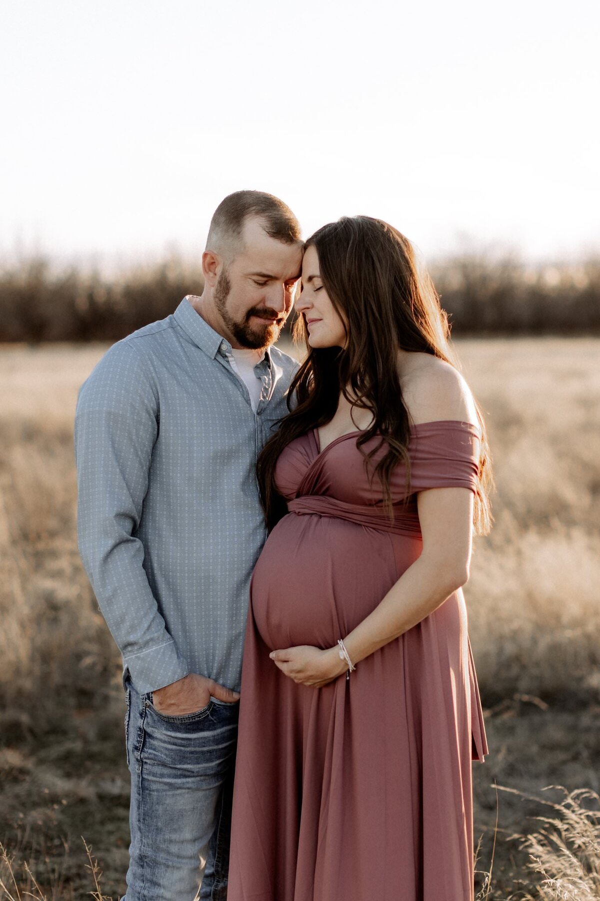 maternity photo of mama holding belly in open field