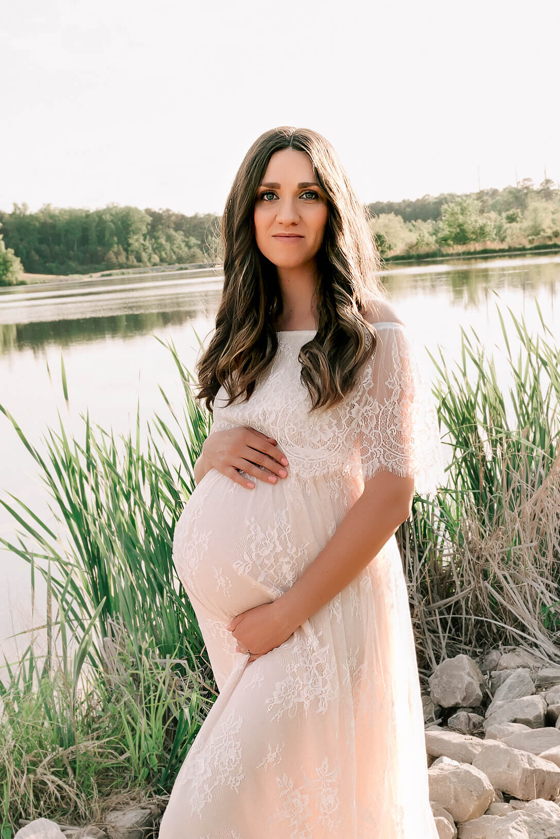 pregnant woman wearing a maternity gown and posing for photographer in raleigh