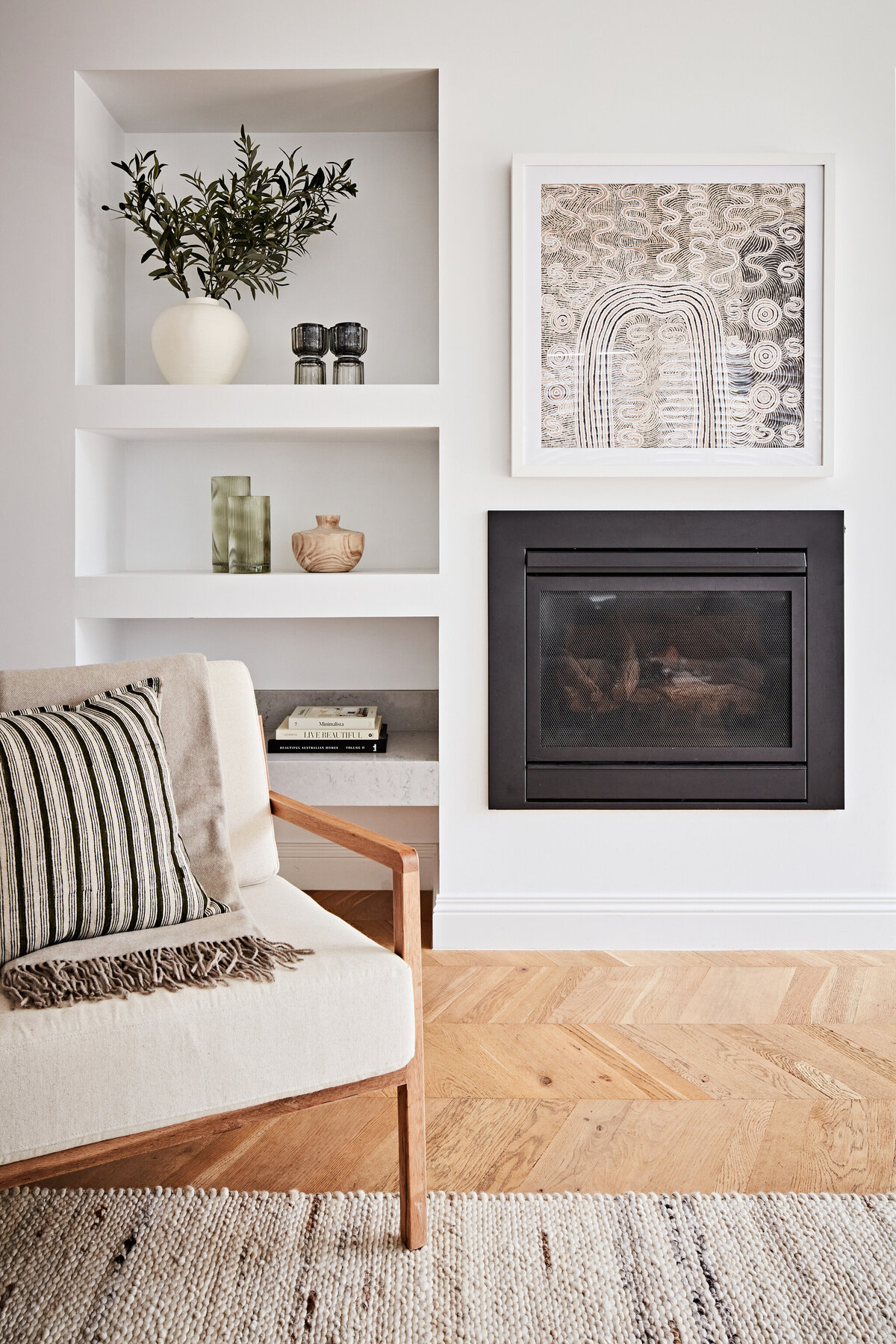 Hampton East living room with custom shelving, fireplace, and modern armchair
