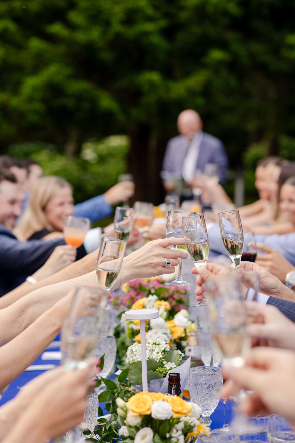 Guests cheering and clinking glasses during rehearsal dinner speeches