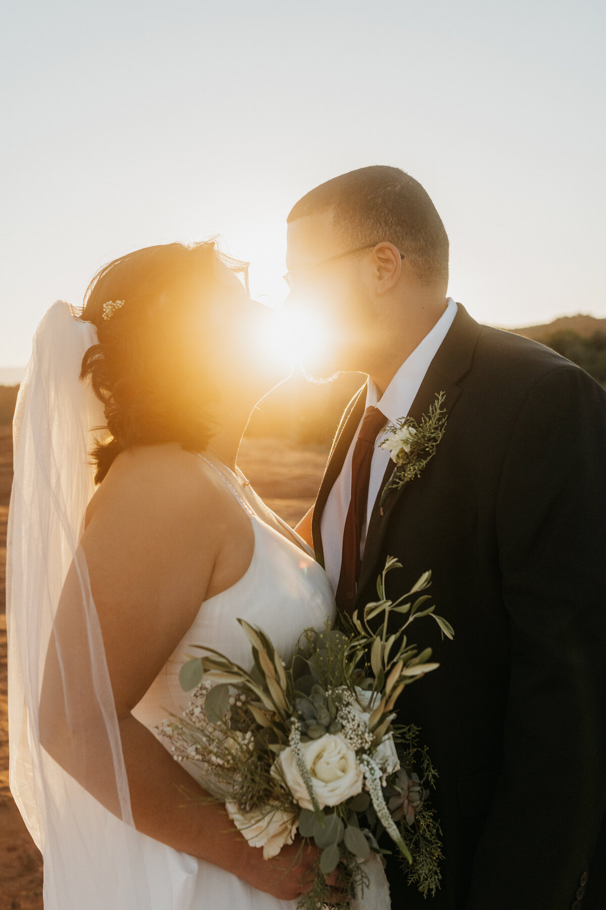 The sun shinning through a couple leaning in for a kiss 