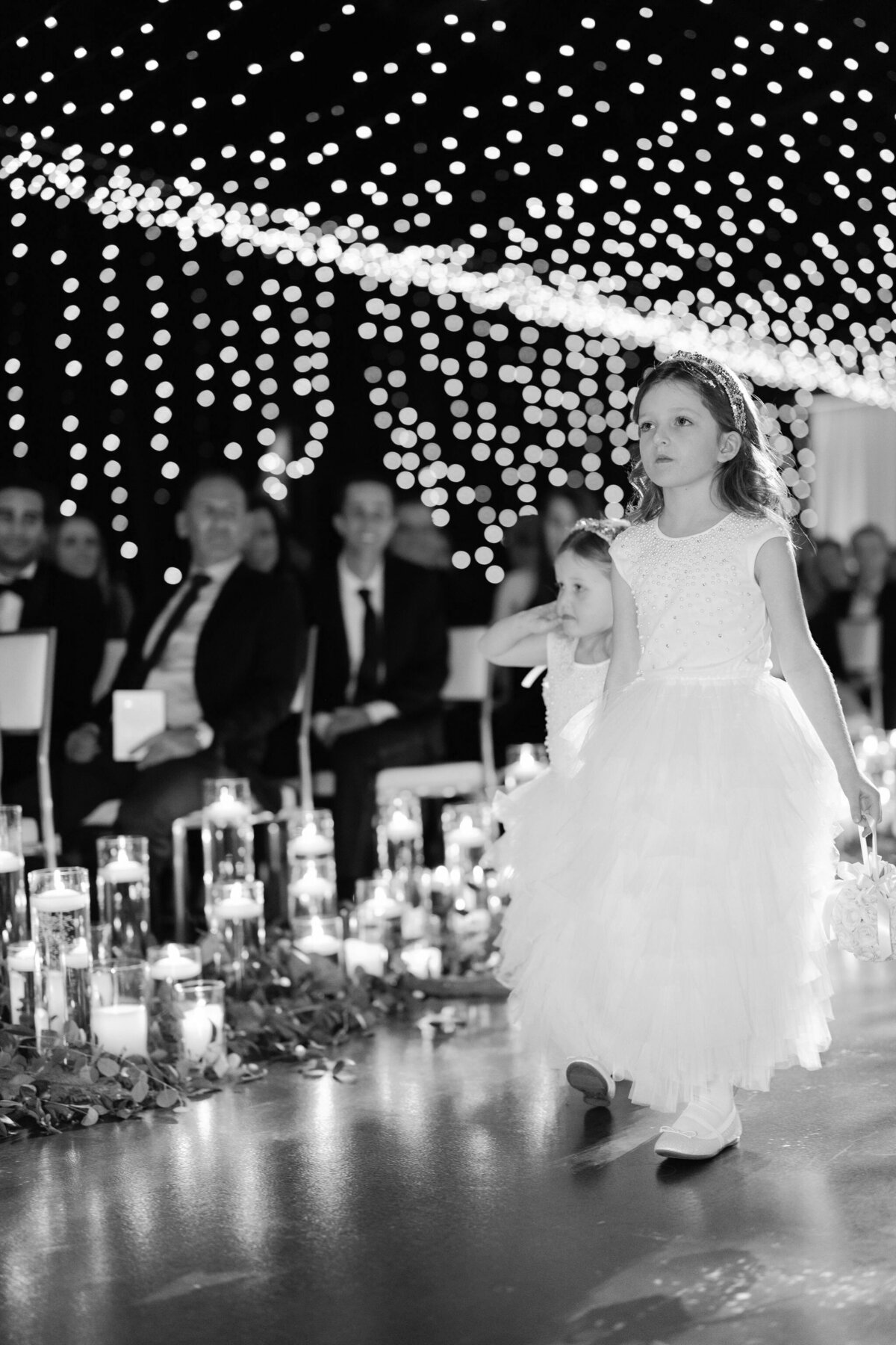 An up close and black and white photo of a flower girl walking down the aisle. 