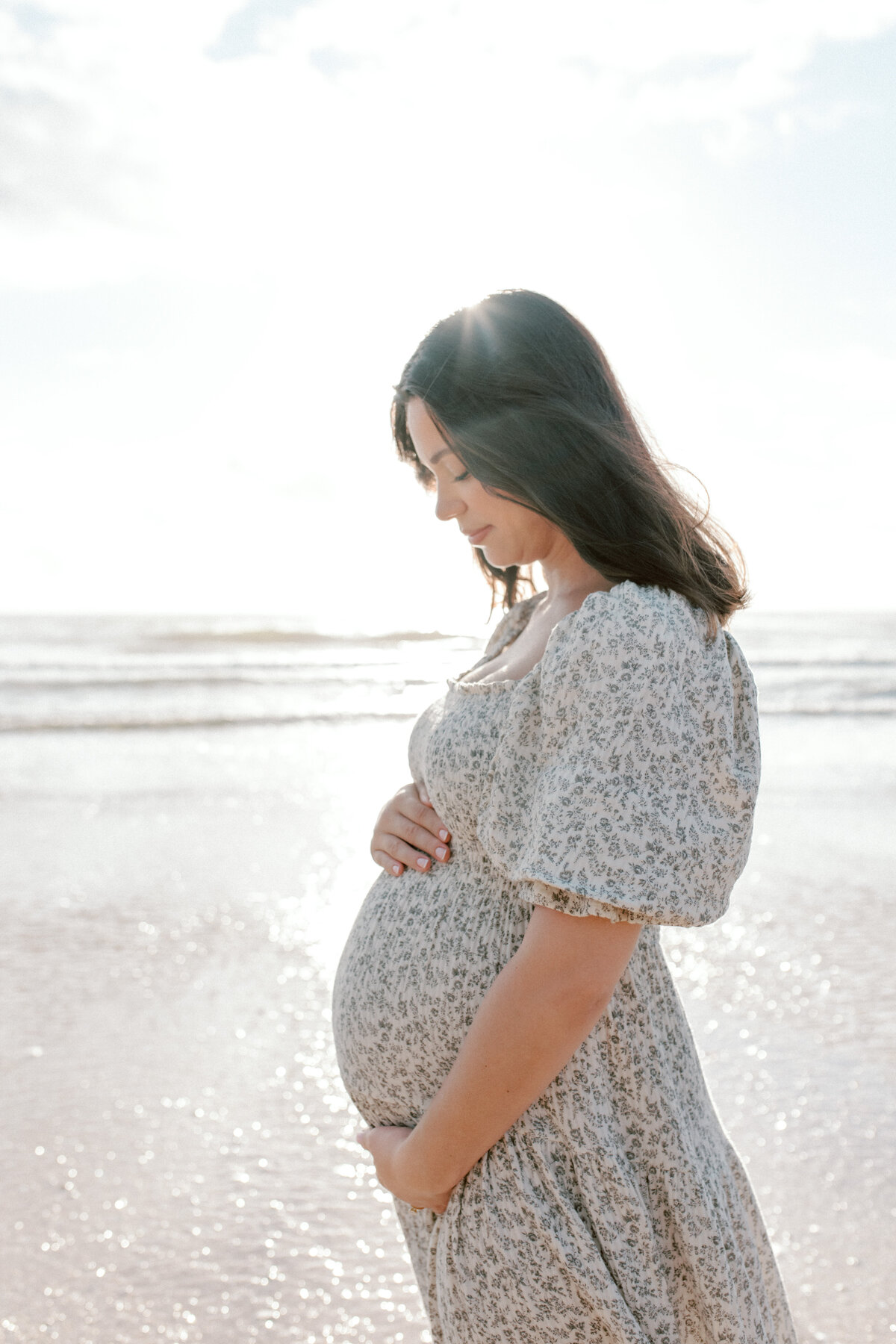 Maternity portrait taken at Vilano Beach near Jacksonville with mom wearing a blue patterned dress and holding her growing belly