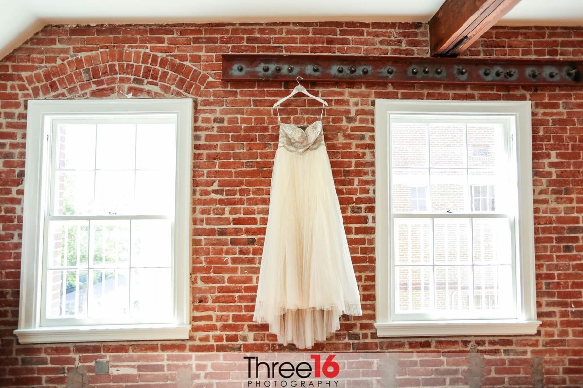 Bride's Dress hanging against a brick wall