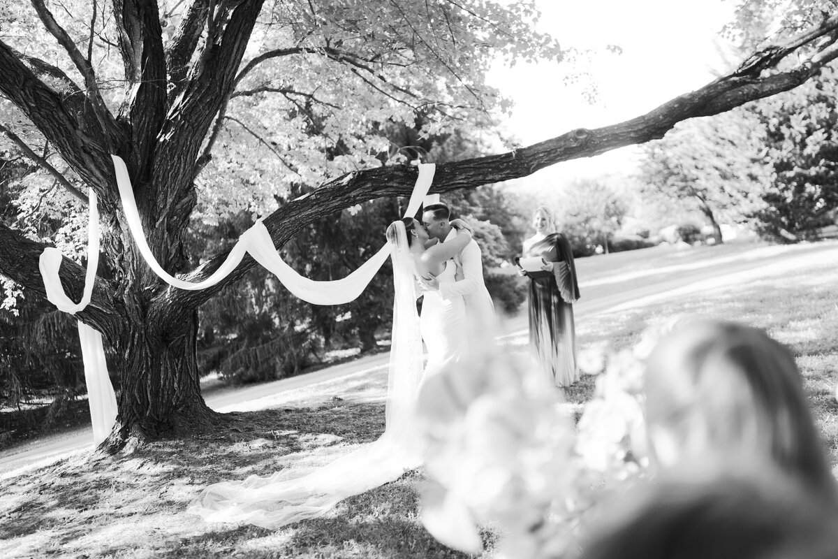 A bride and groom sharing their first kiss under a maple tree during a Tennessee backyard wedding. 