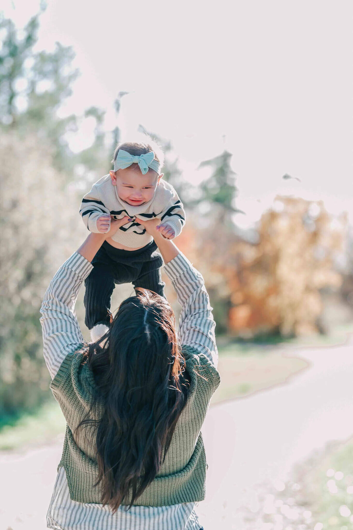 Mom holding baby in the air and smiling at each other. 