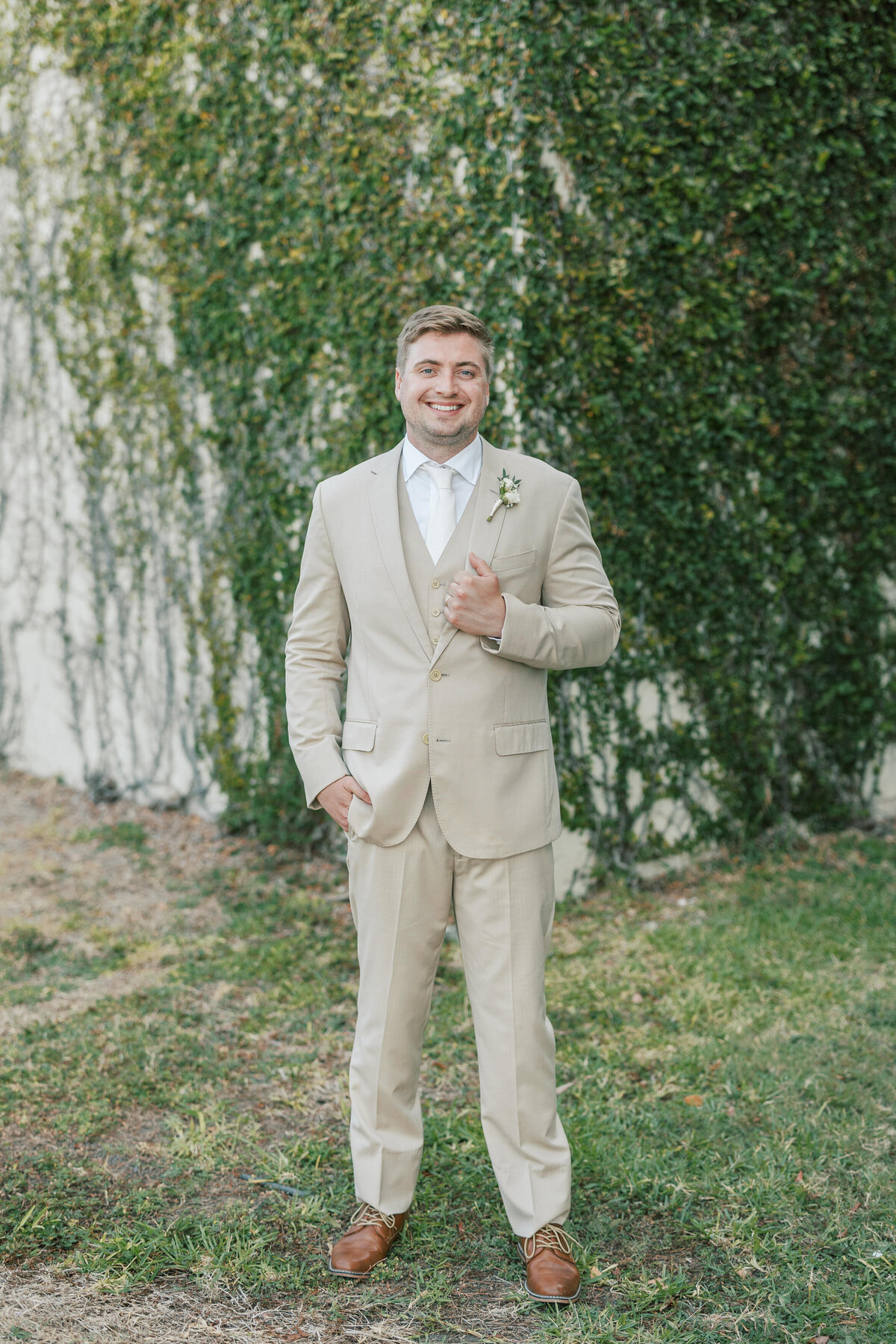 Groom poses solo in tan suit at Cancun wedding venue, captured by a Philadelphia-based photographer.