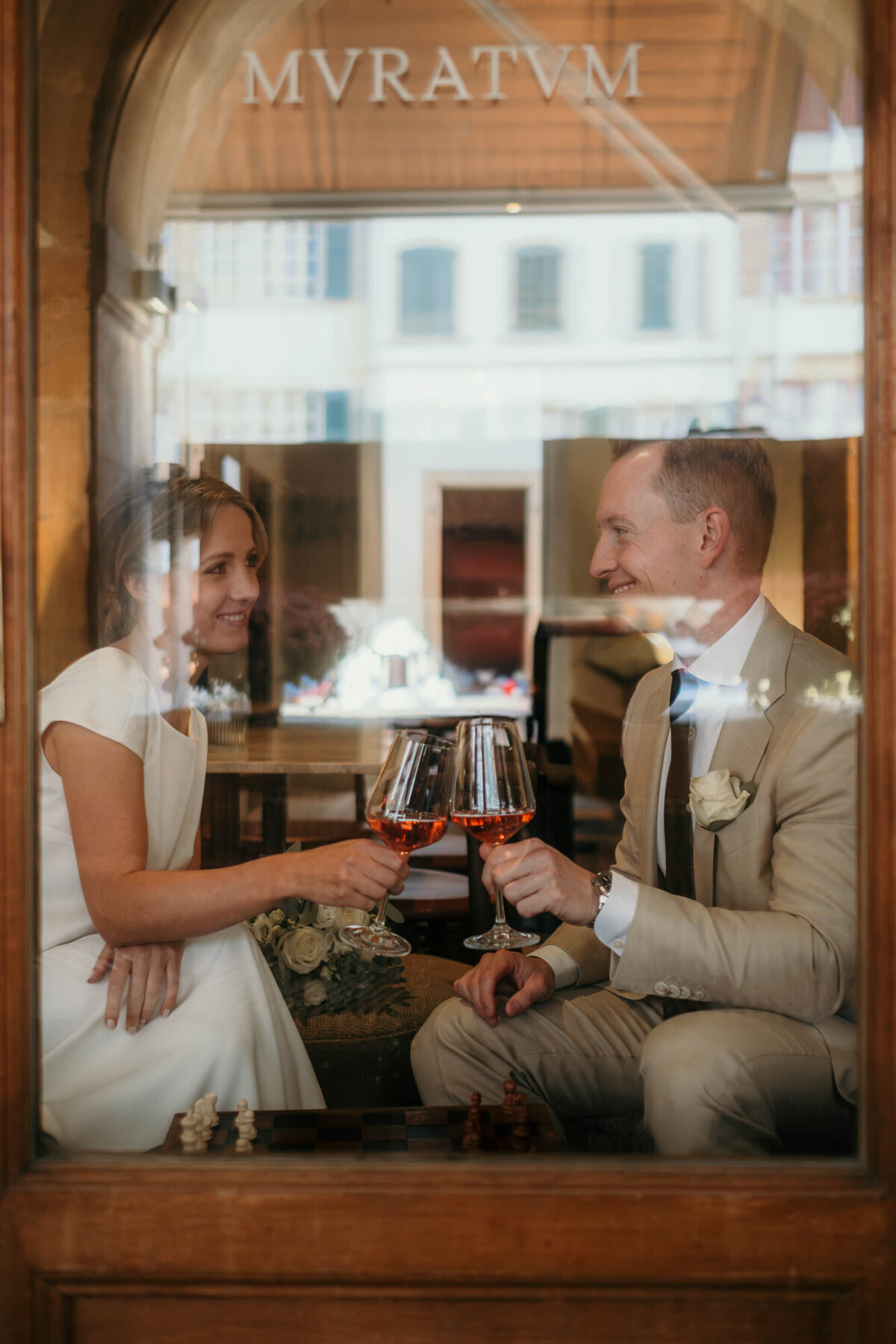 The wedding couple holds their Aperol glasses to cheer to oneanother while looking each other deep in die eyes.