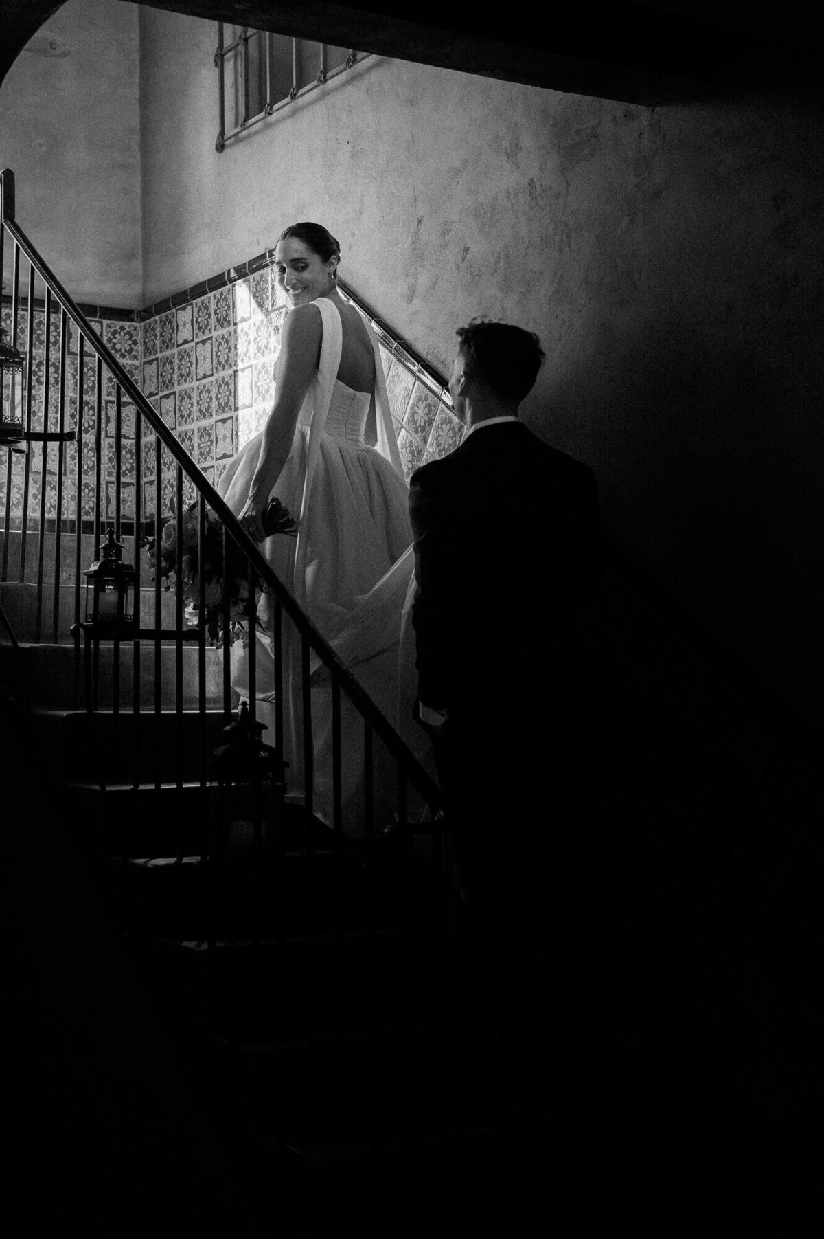 Bride smiling back at her groom while walking up the tiled staircase at Royal Palms, captured by a Scottsdale wedding photographer.