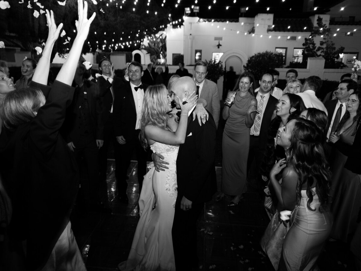 bride and group kissing as wedding guests cheer