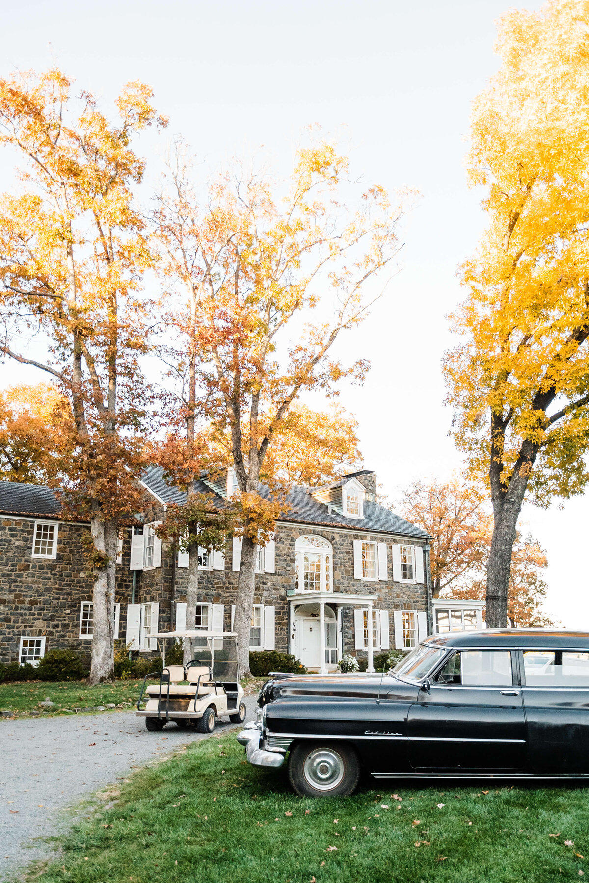 Virginia wedding photographer captures Murray Hill venue in the fall with a vintage car out front and the sun shining through the trees at sunset