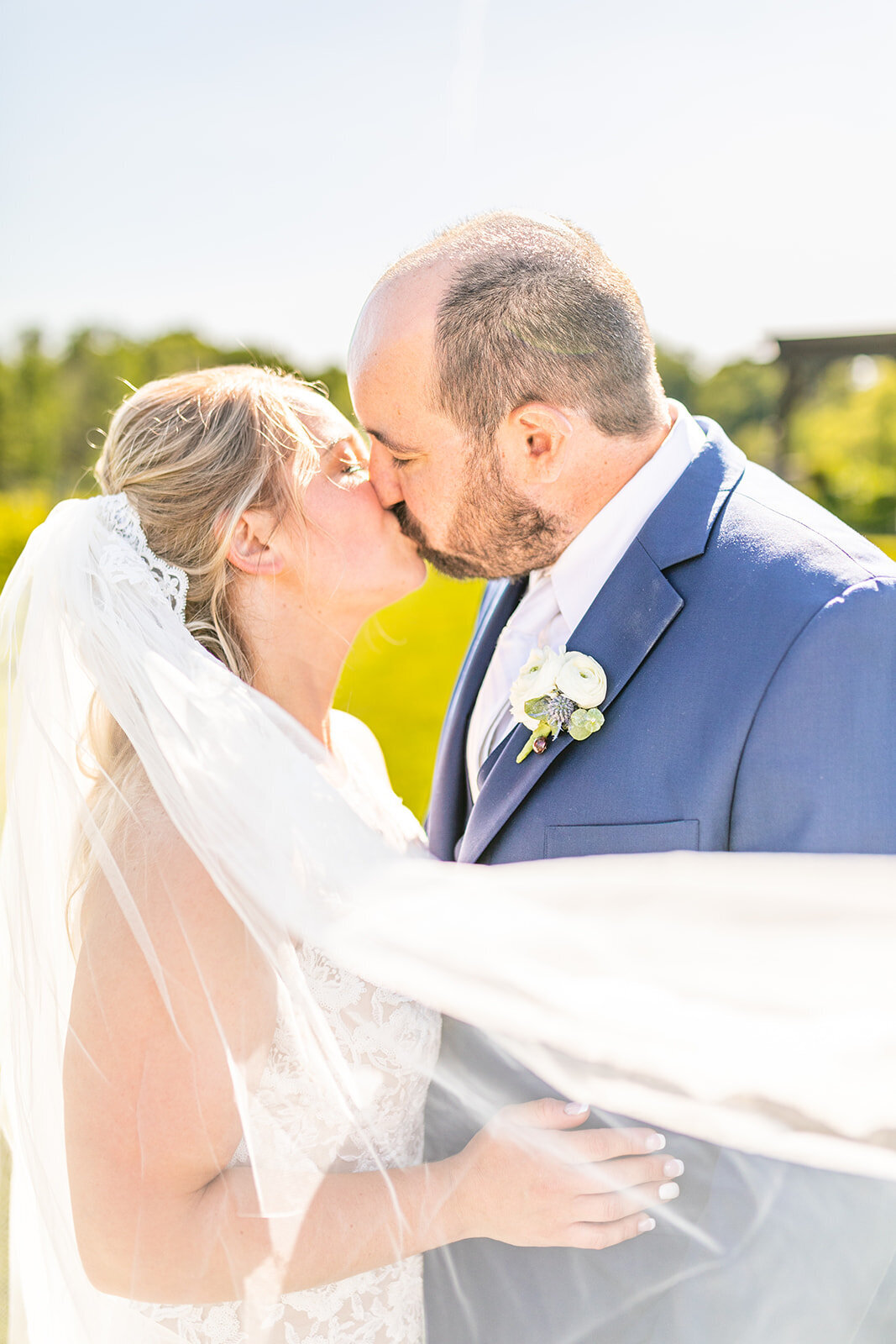 Bride and groom kissing with veil