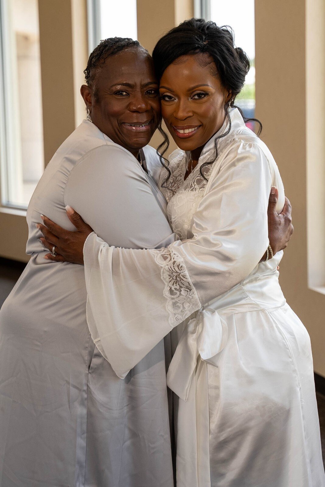 bride-with-mom-in-law-hugging-in-bridal-suite-duneland-falls