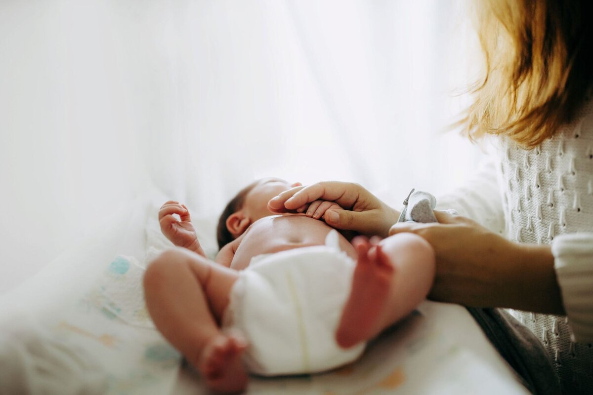 mom holding newborn babys hand with bright light in nursery by Francesca Marchese Photography