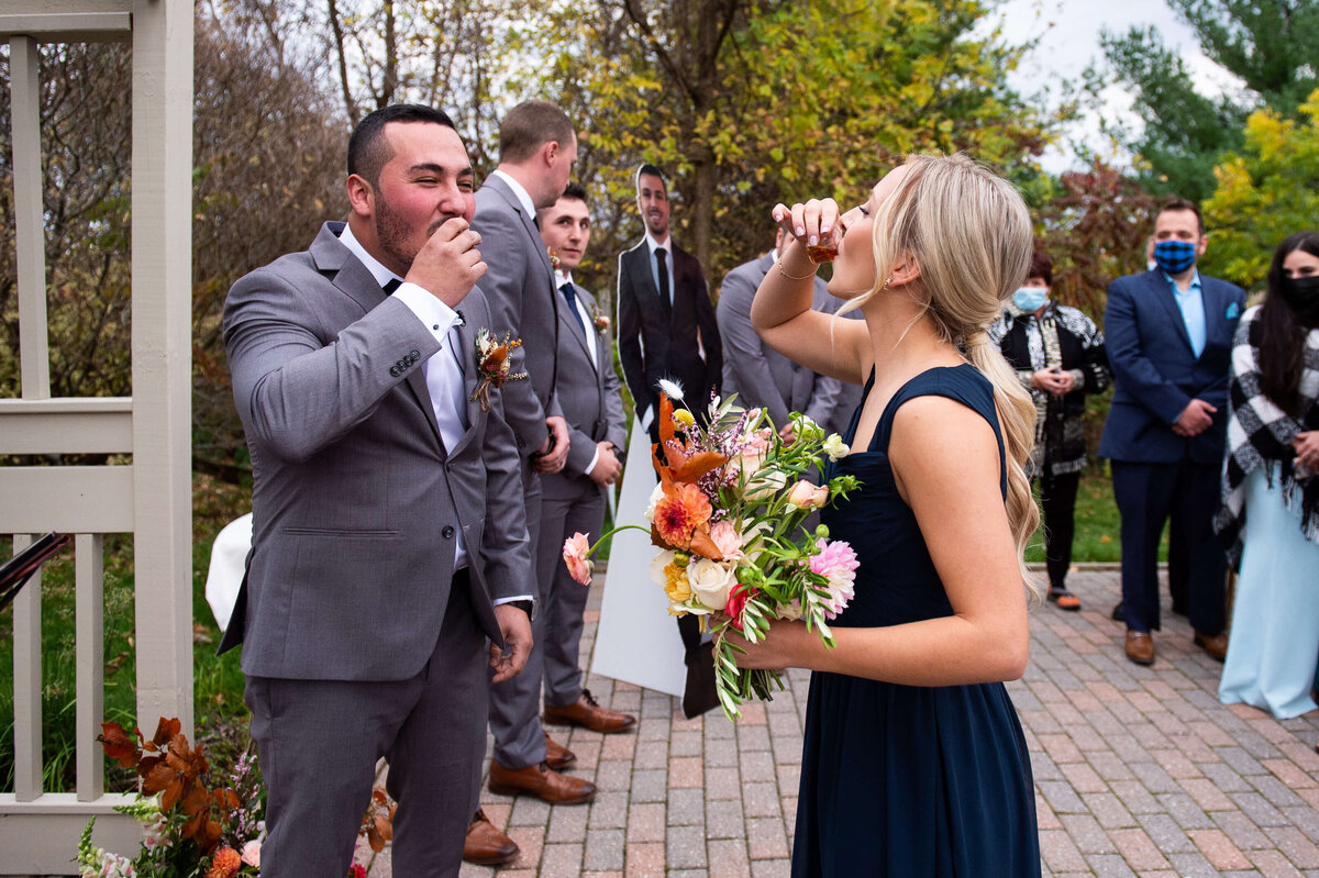 a bridesmaid takes a shot with the groom at the ceremony site.  Taken by Ottawa wedding photographer JEMMAN Photography