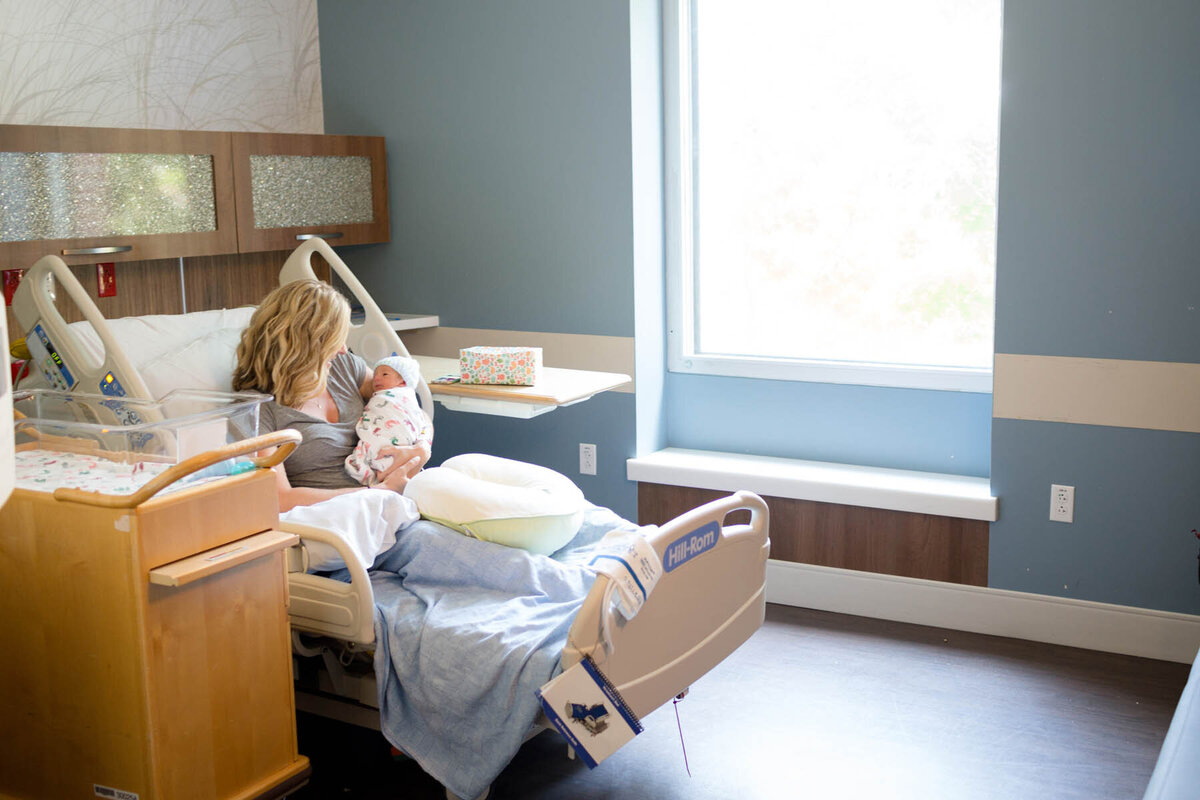 mother holds her newborn baby in her hospital room hours after giving birth