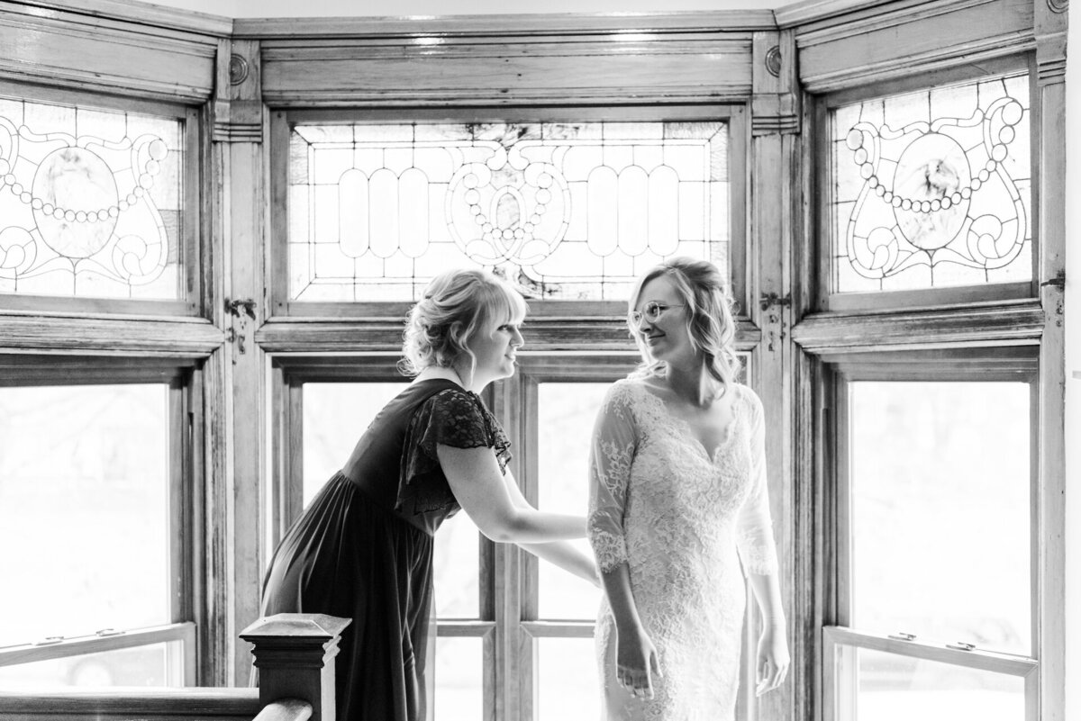 a woman helping a bride with her wedding dress