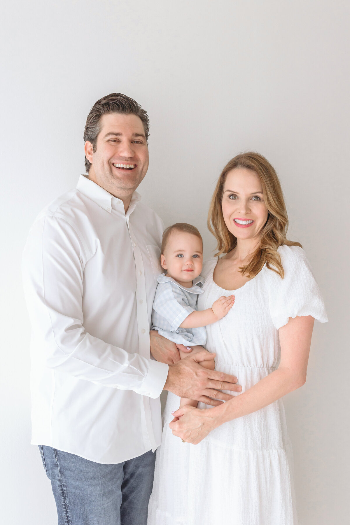 mom holding toddler and dad hugging them