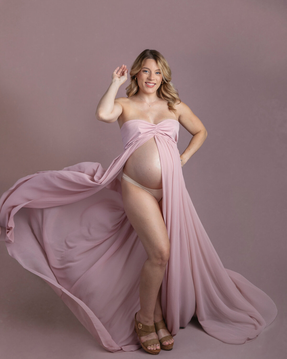 Maternity portrait of a beautiful woman wearing a pink maternity gown