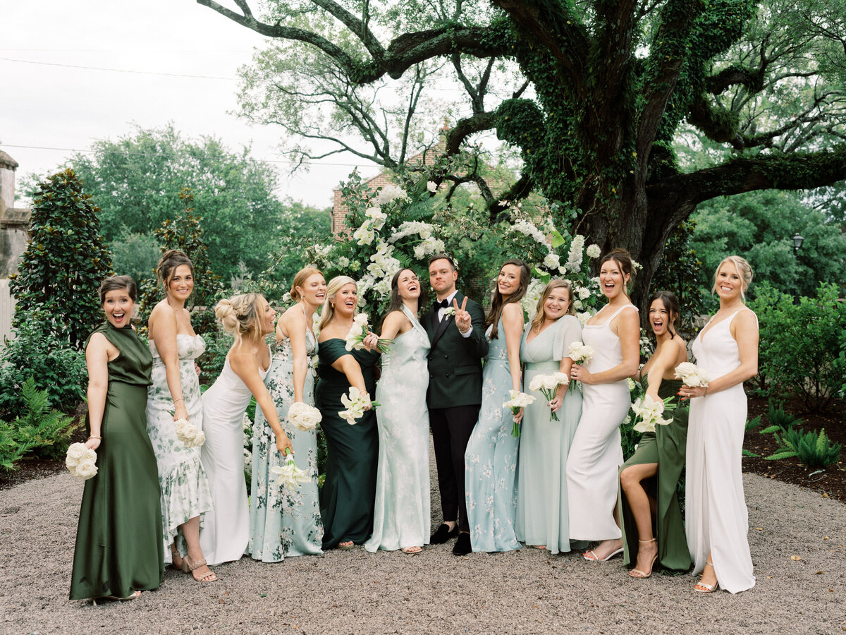A stunning group of bridesmaids pose joyfully with the grooms, showcasing their beautiful dresses and the happiness surrounding this unforgettable wedding moment.
