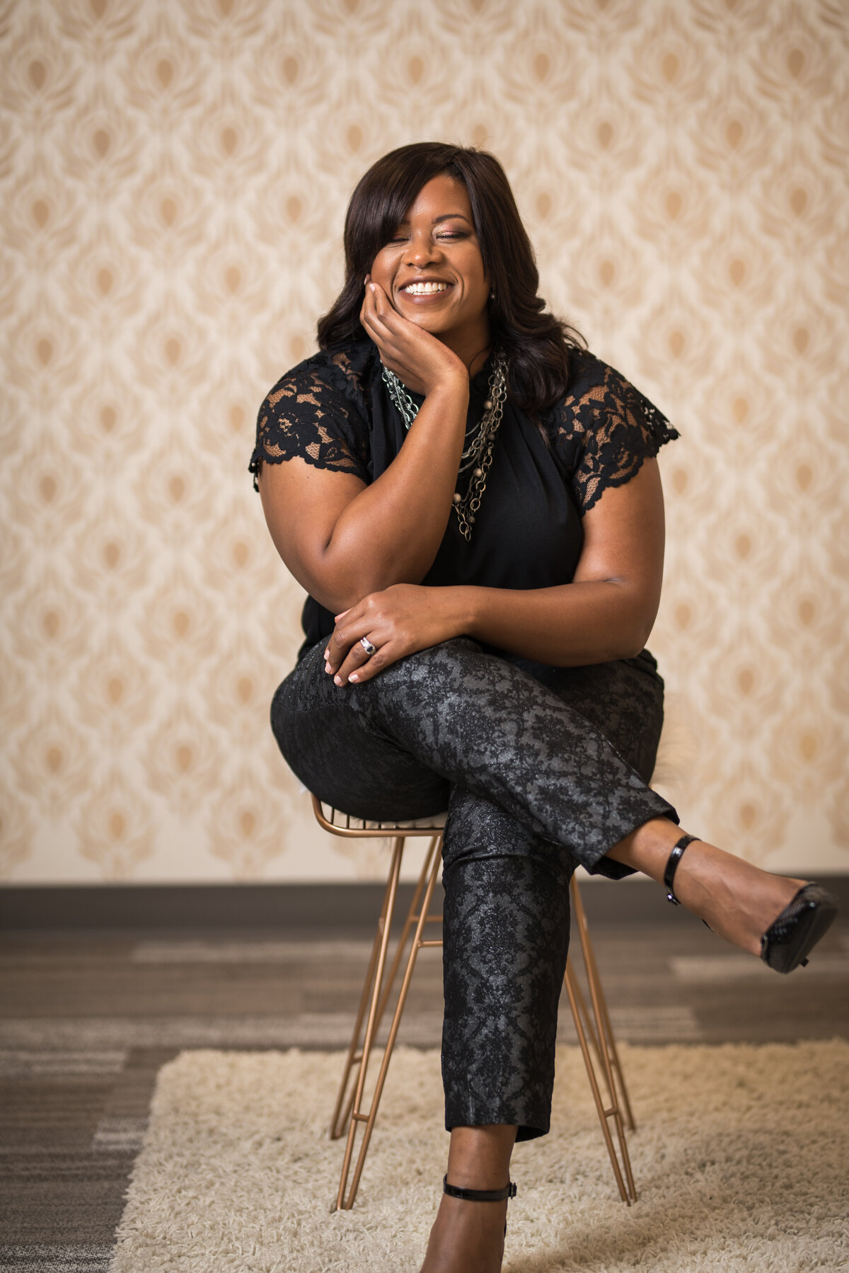 Woman sitting on chair in all black laughing