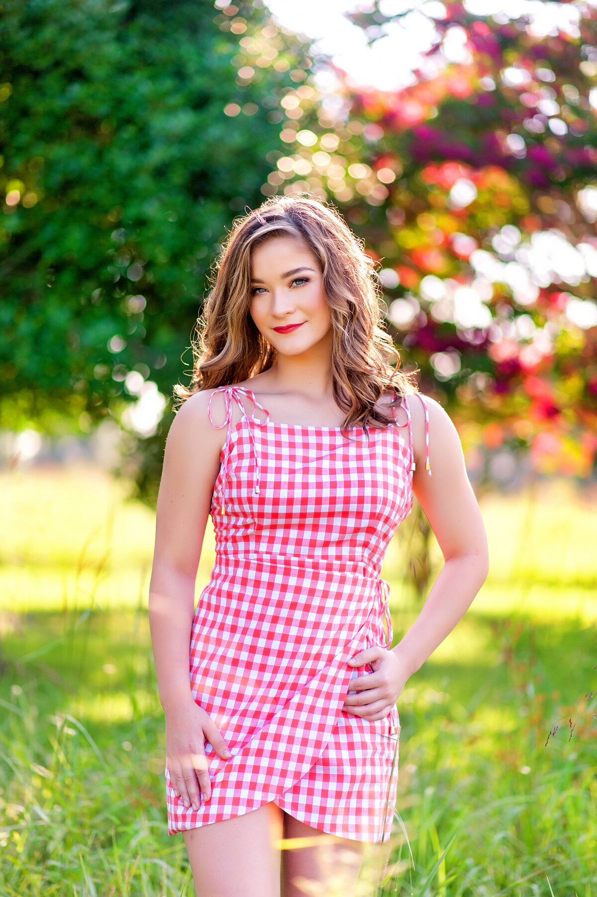 Mechanicsville high school senior girl poses in field wearing a red and white gingham dress.