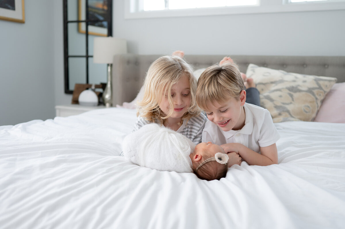 Siblings on the bed with their new baby sister