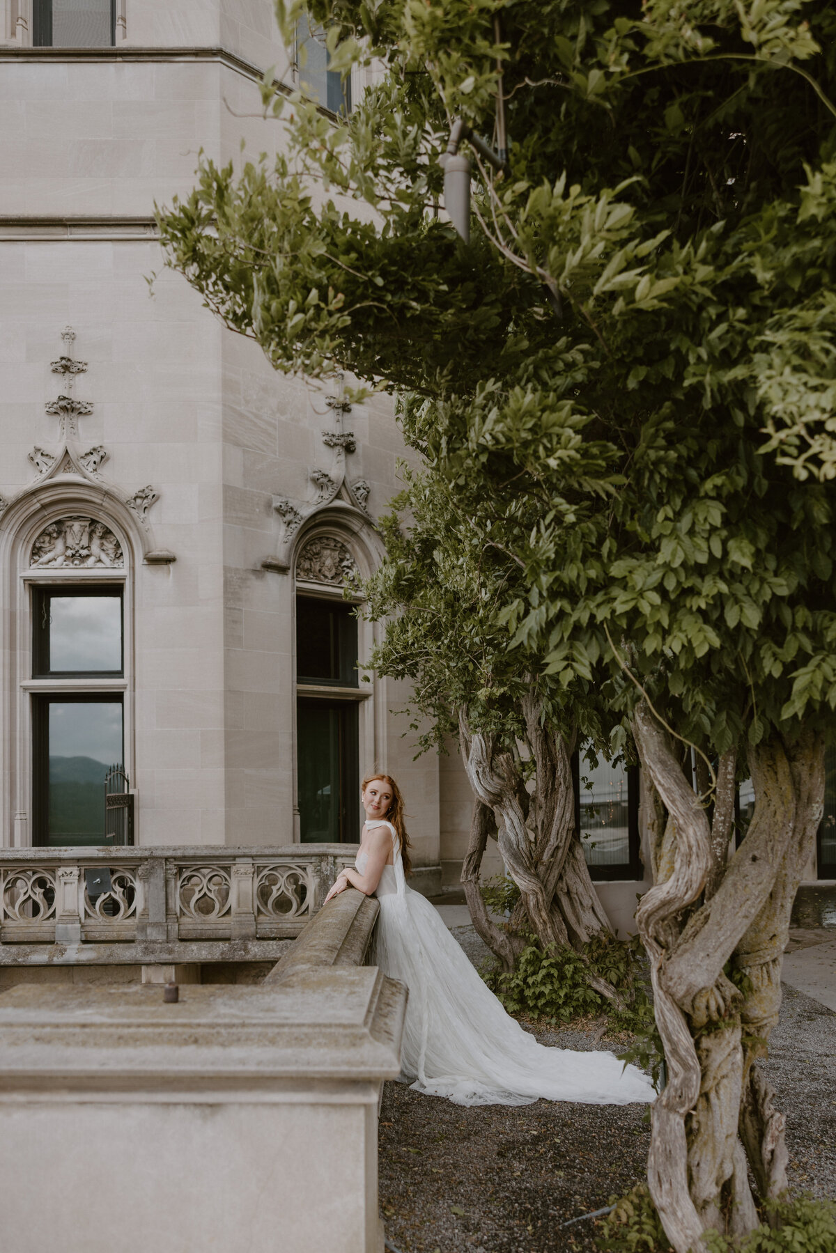 Soft wind catching the bride’s veil and skirt while she poses in front of Biltmore’s grand facade.