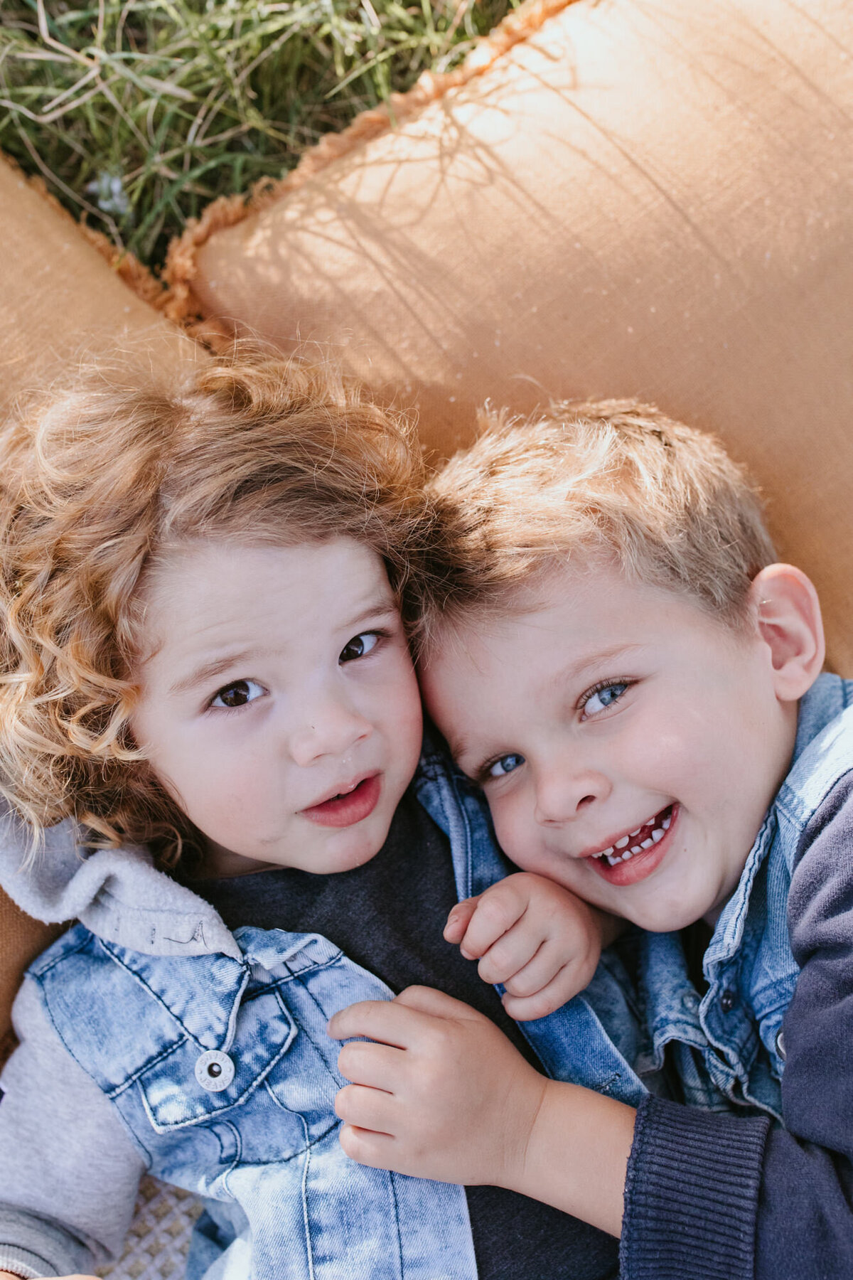 Documentary-style photo of two brothers lying head to head while smiling, taken by a Bendigo Family Photographer. 