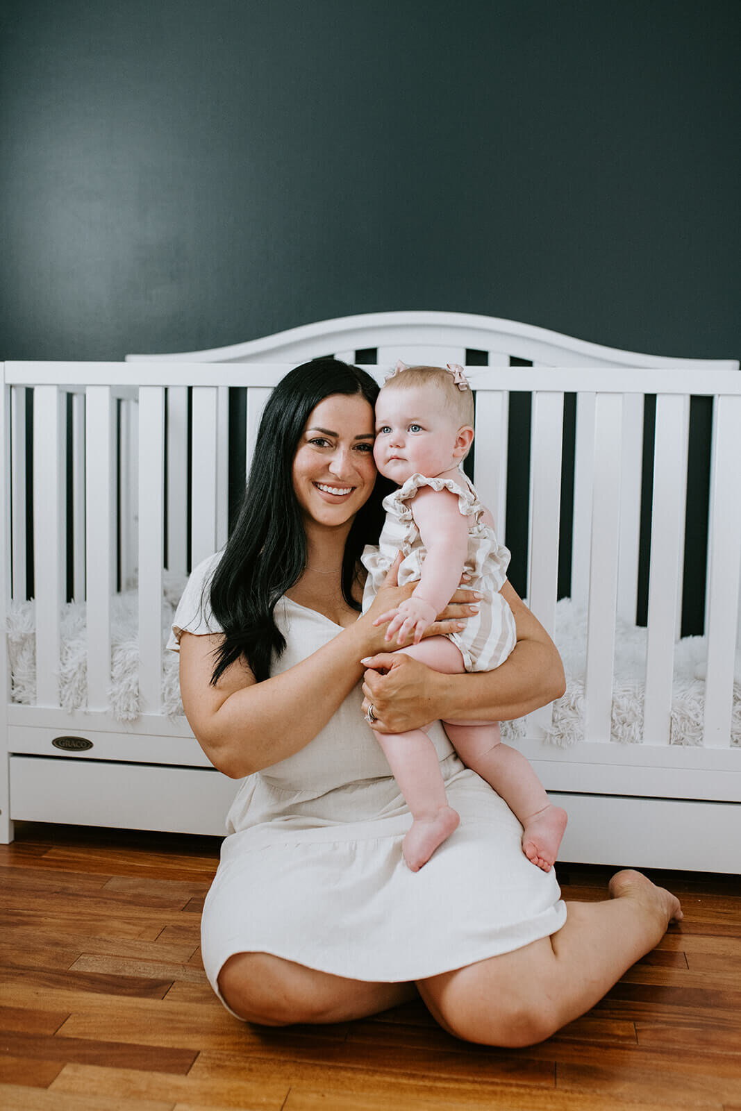 Mother-holding-baby-girl-in-front-crib
