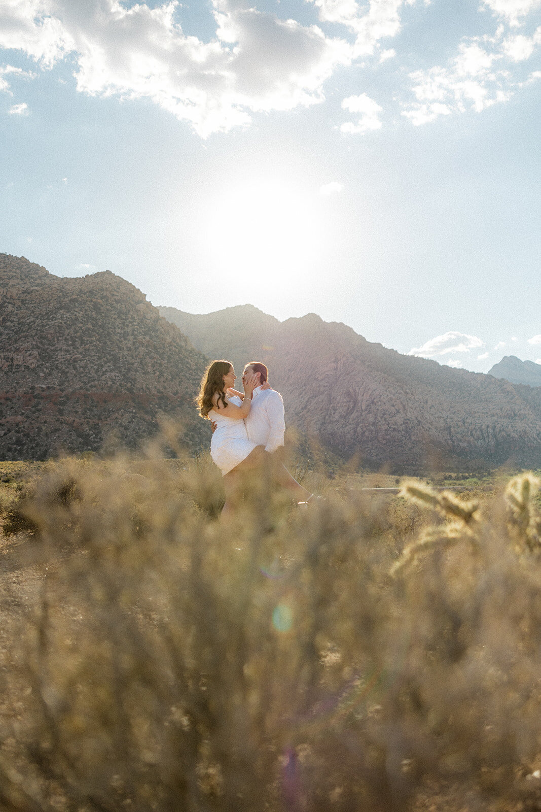 Man holding his fiance's leg up with mountains in the back in Nevada
