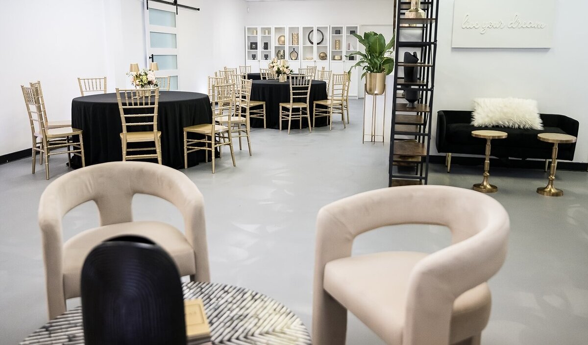 Chic Memphis event venue setup at The Parlor at Wells featuring black round tables, gold chiavari chairs, modern lounge seating, and elegant shelf décor—ideal for intimate gatherings, showers, and creative workshops.