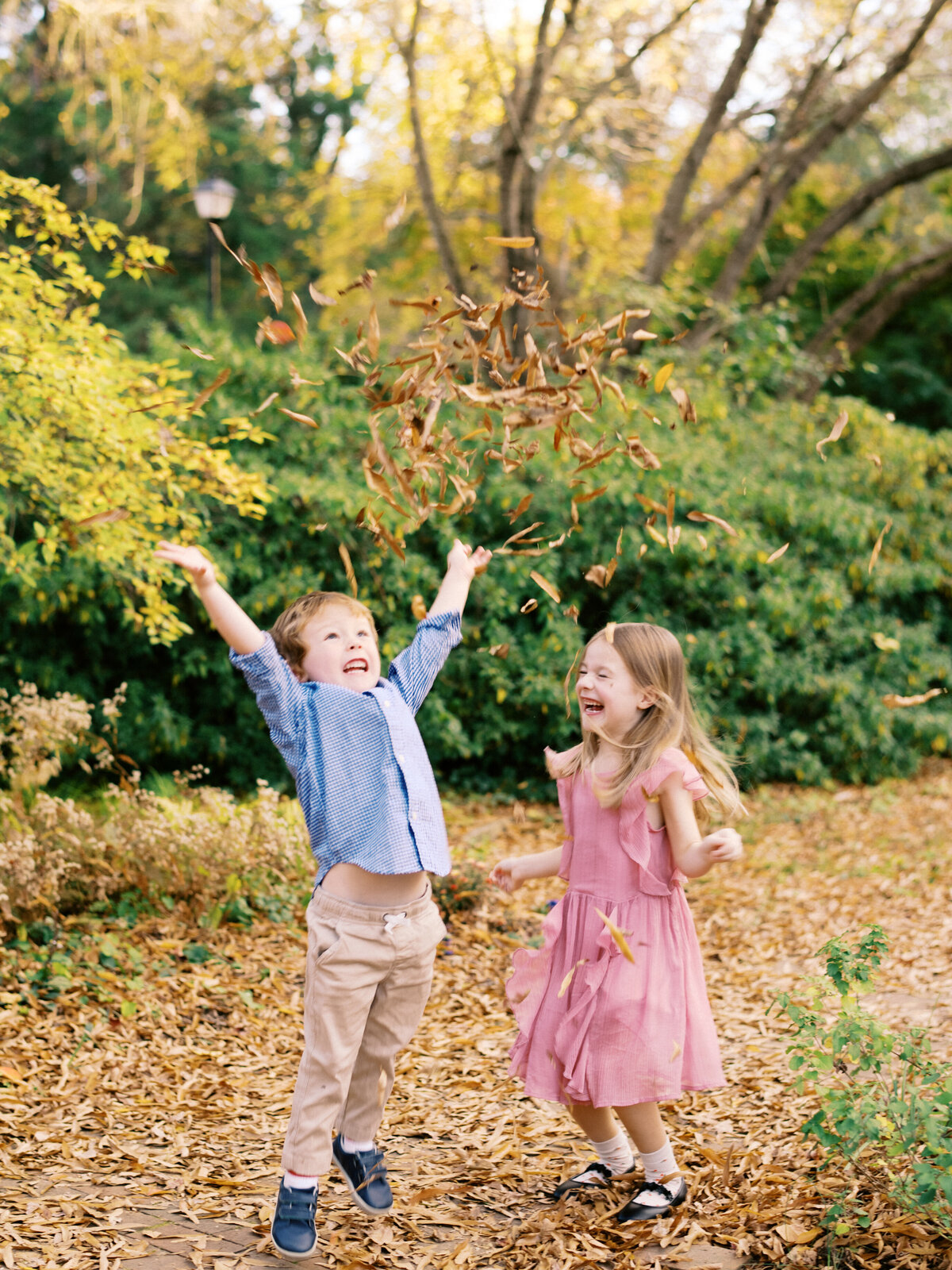 Siblings laugh and play in the leaves during this fall photo. Image by Raleigh maternity photographer A.J. Dunlap Photography.