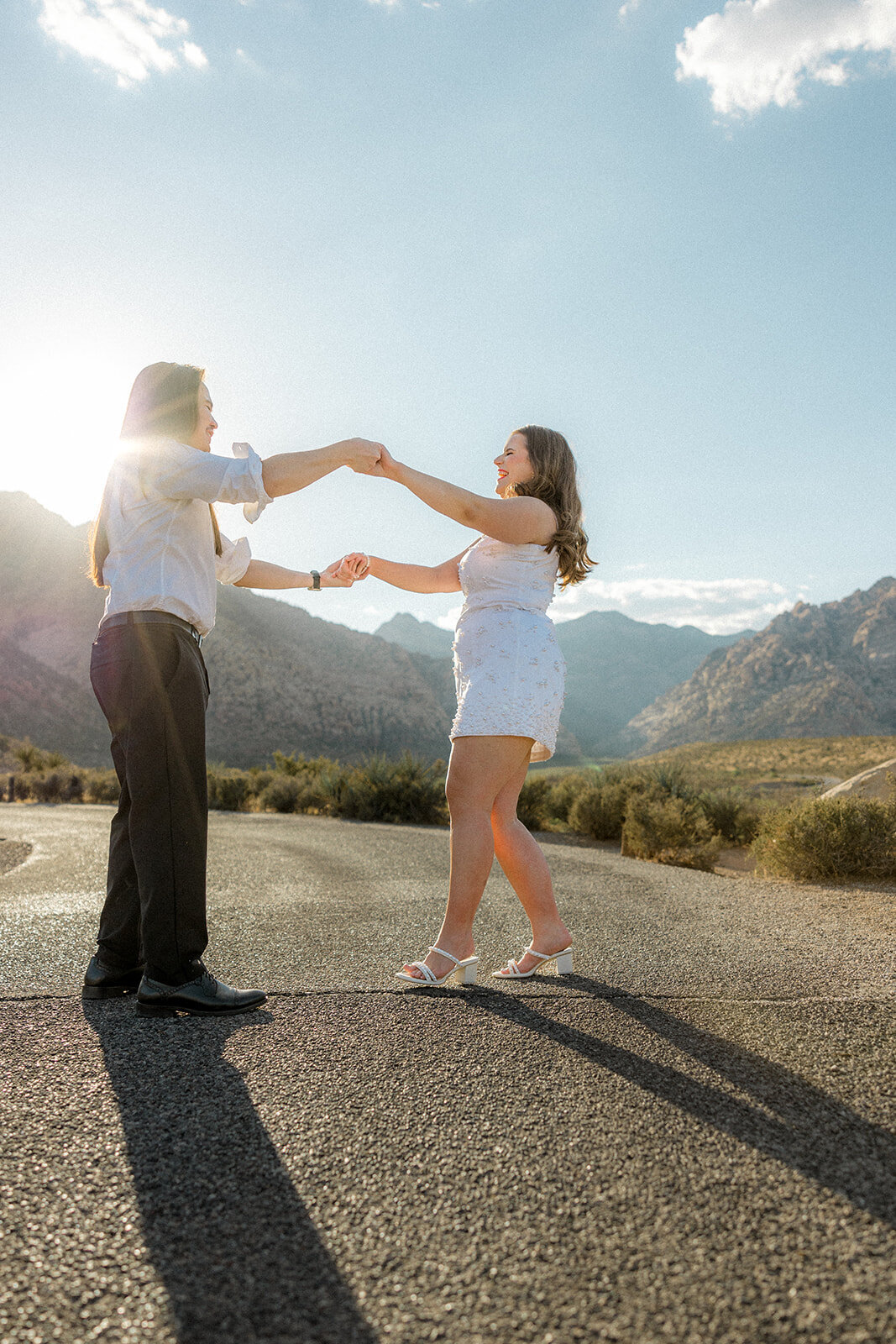Engaged couple dancing on empty road with Nevada mountains in the back