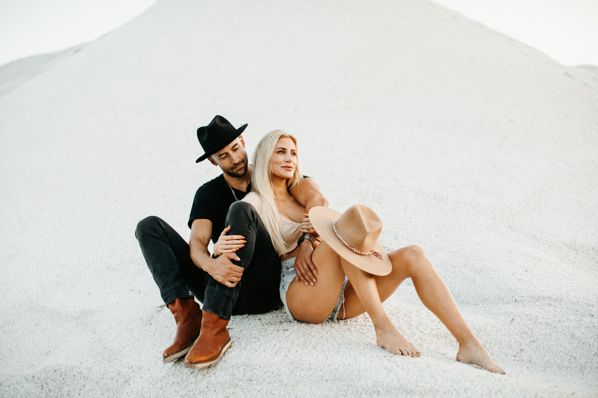 couple sitting in the sand cuddling