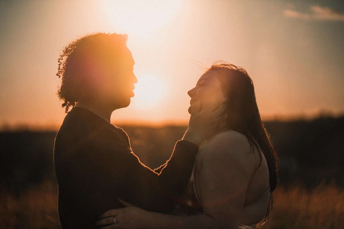 A young couple kisses in the sunset on a farm in Tennessee.