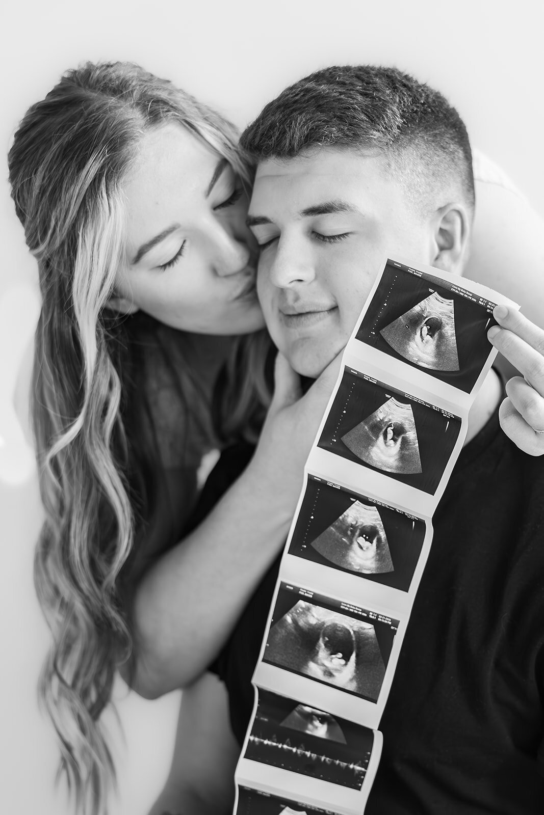 Couple smiling next to their ultrasound phhotos