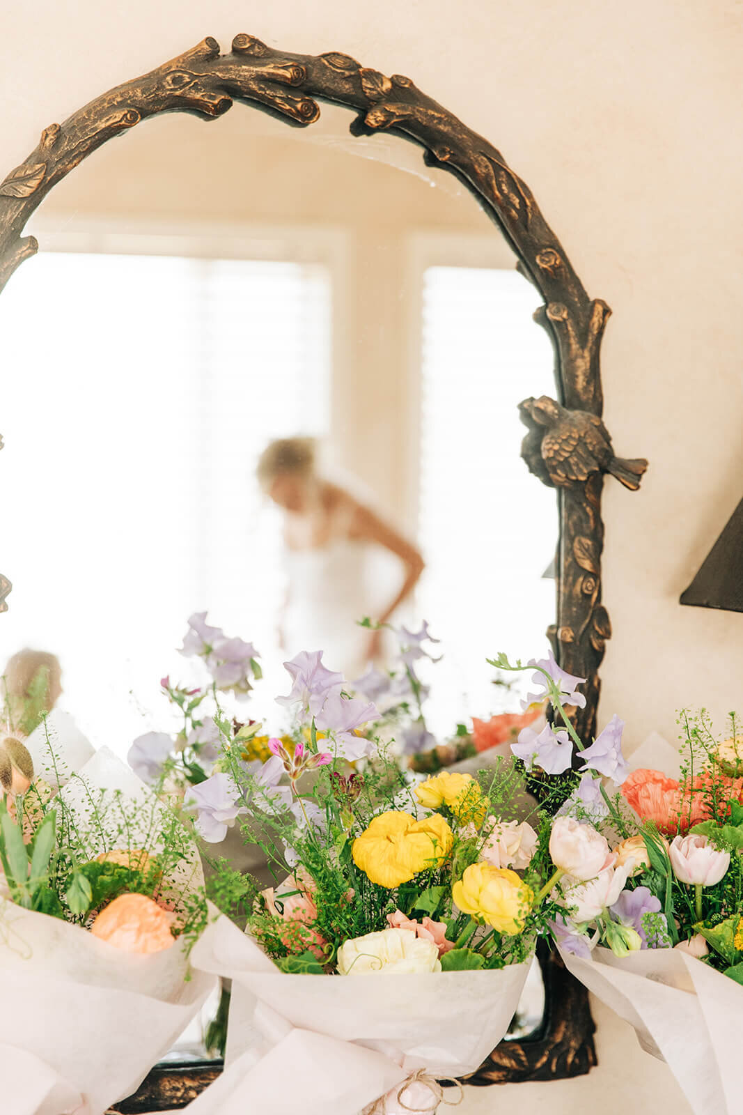Wedding flowers and a blurred reflection of the bride through a mirror.