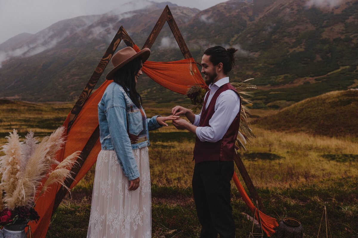 A groom puts a ring on his bride's finger as he commits his life to her