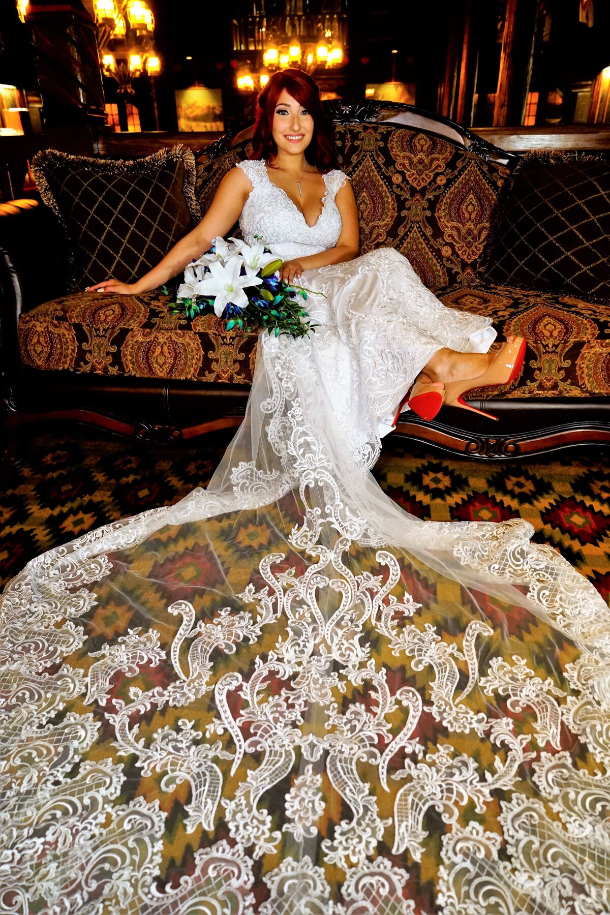 A smiling bride sits gracefully on a sofa, showcasing her elegant wedding attire in a relaxed and intimate setting. This image highlights the beauty and joy of bridal portraits, capturing a candid and stylish moment that reflects the essence of our wedding photography.