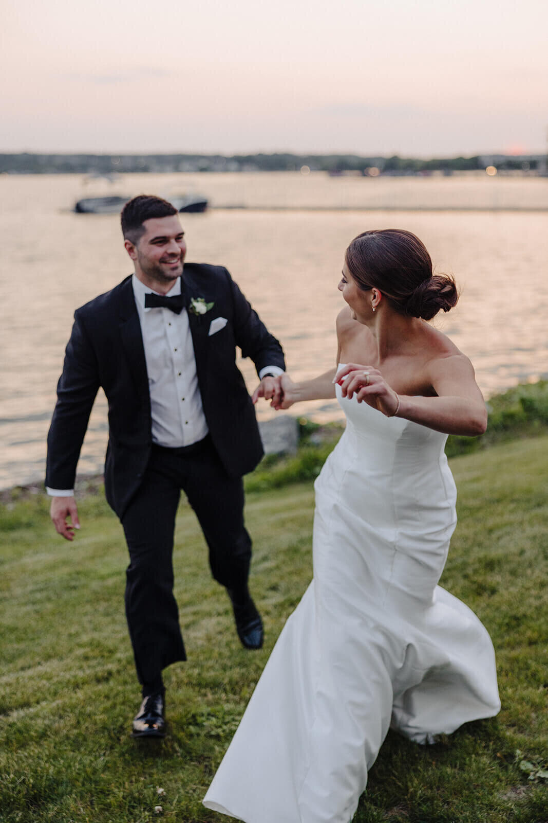 Bride and groom running alongside the lake at Canandaigua Country Club, NY