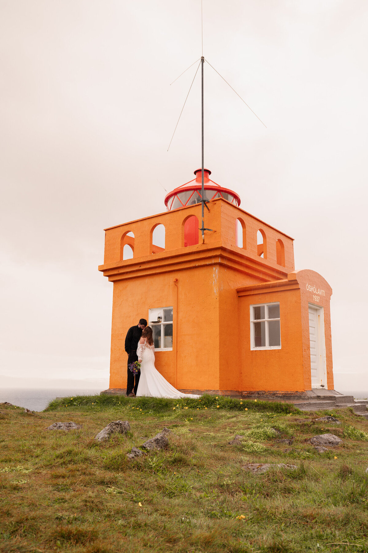 A bride and groom share a kiss at one of Iceland's historic lighthouses in the Westfjords of Iceland near the town of Ísafjörður.