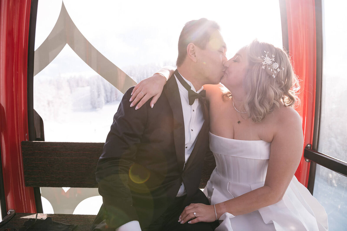 Bride and groom sharing a kiss inside a ski gondola at St. Regis Aspen, surrounded by stunning mountain views and natural light.