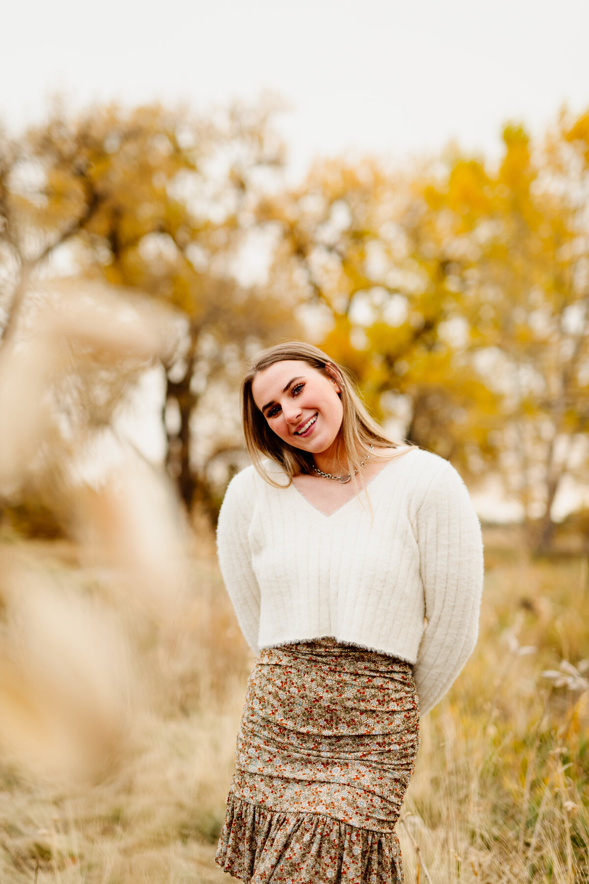Boho chic senior in a field smiling for her Rocky Mountain High School senior photoshoot