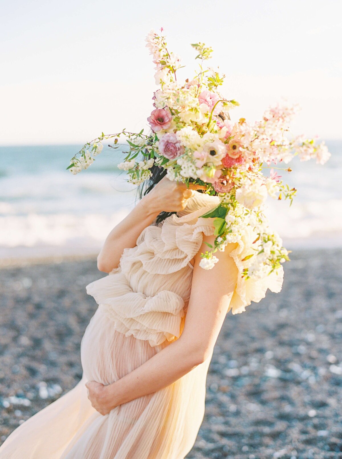 maternity photography in san francisco bay area beach with pregnant woman holding florals