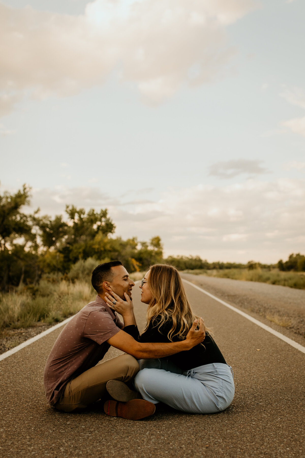 engaged couple sitting on a bike trail in Albuquerque about to kiss