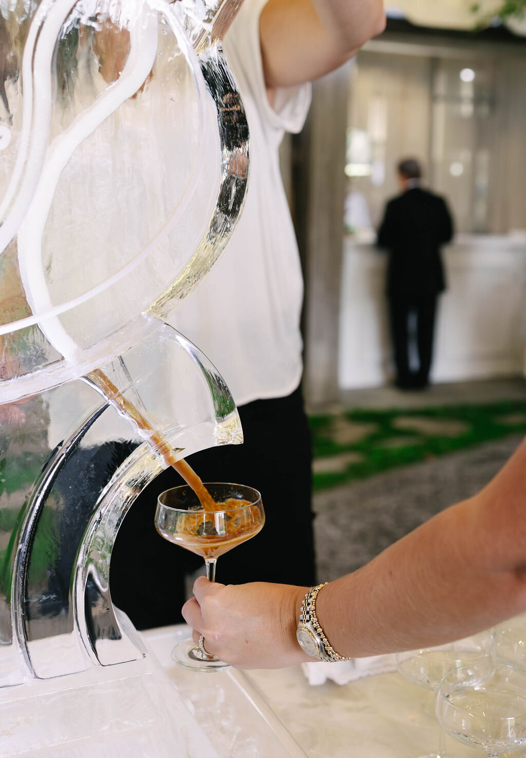 Guest pouring an espresso martini from a custom ice luge during cocktail hour at a Bascom Center wedding in Highlands, North Carolina.