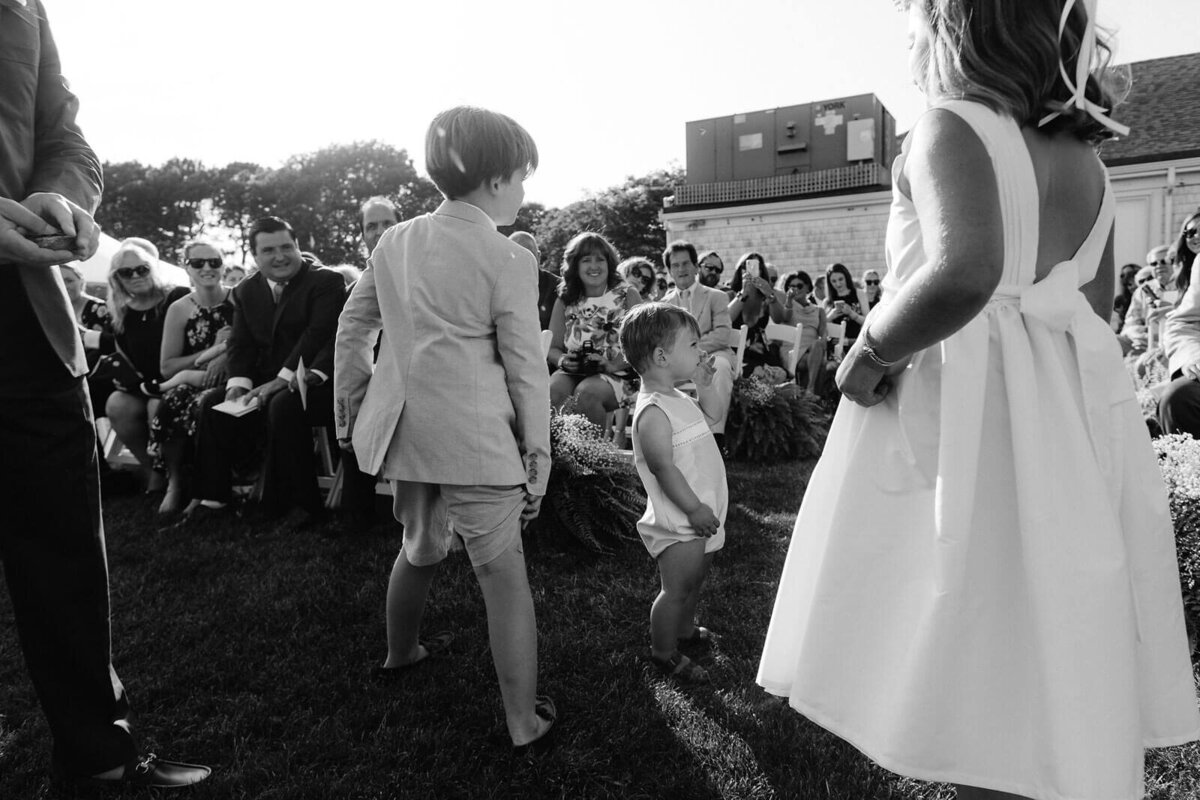Black and white photo of a baby and two older children in front of wedding guests in an outdoor wedding at Cape Cod, MA.