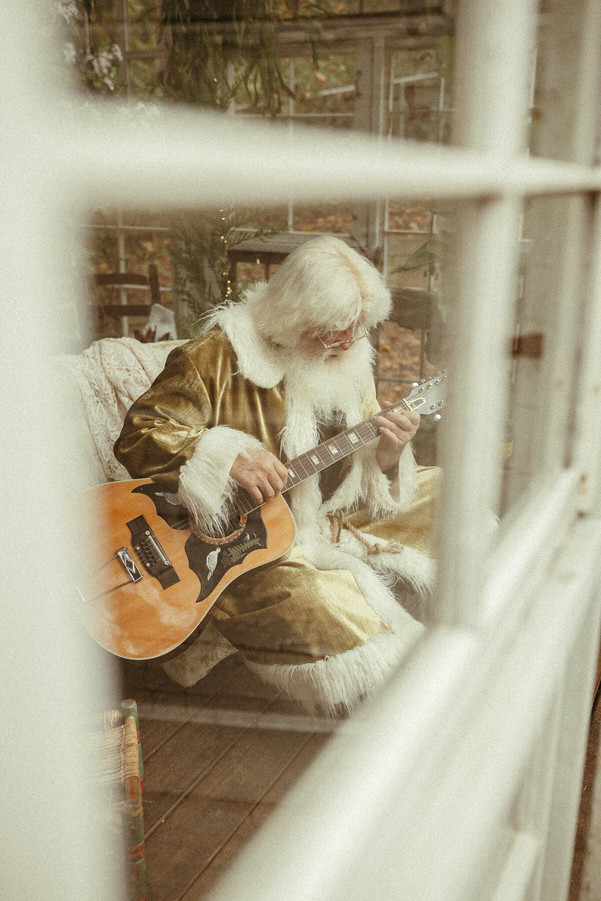 Santa playing the guitar in gold velvet Santa clothes. 